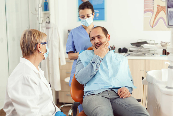 Medico stomatologo che parla con paziente uomo con mal di denti - Foto, immagini