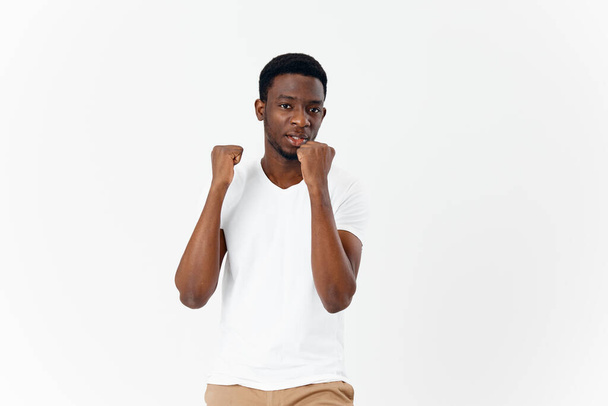 afrikkalainen näköinen mies elehtii kädet studio valkoinen t-paita eristetty tausta - Valokuva, kuva