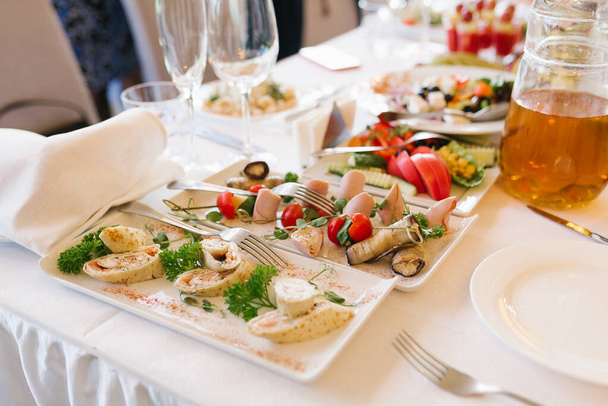 Občerstvení na bílých talířích na slavnostním banketovém stole na svatbě - Fotografie, Obrázek