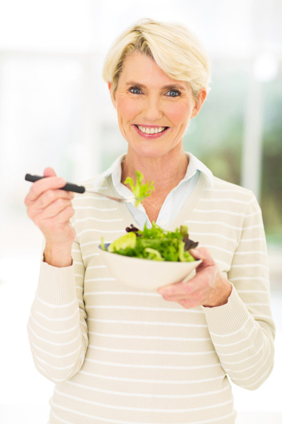 Middle aged woman eating salad - Фото, зображення