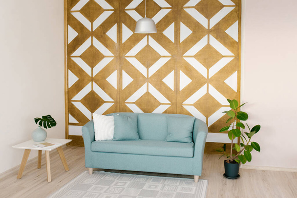 Obývací pokoj ve skandinávském stylu. Geometrický vyřezávaný panel na stěně, modrá pohovka, vnitřní fíkus rostliny, konferenční stolek v domě - Fotografie, Obrázek