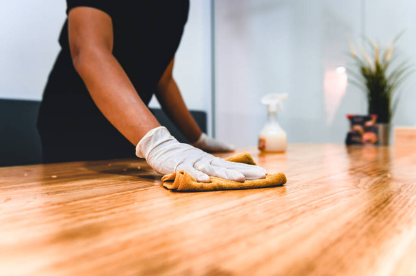 Χέρι σερβιτόρου γυναικών καθαρισμού τραπέζι με απολυμαντικό σπρέι και ύφασμα μικροϊνών για απολύμανση σε εσωτερικό εστιατόριο. Έννοια πρόληψης του ιού του κερατοειδούς. - Φωτογραφία, εικόνα