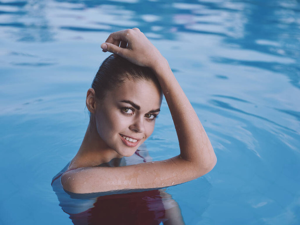 mooie vrouw in zwembad rood badpak luxe hand op hoofd - Foto, afbeelding