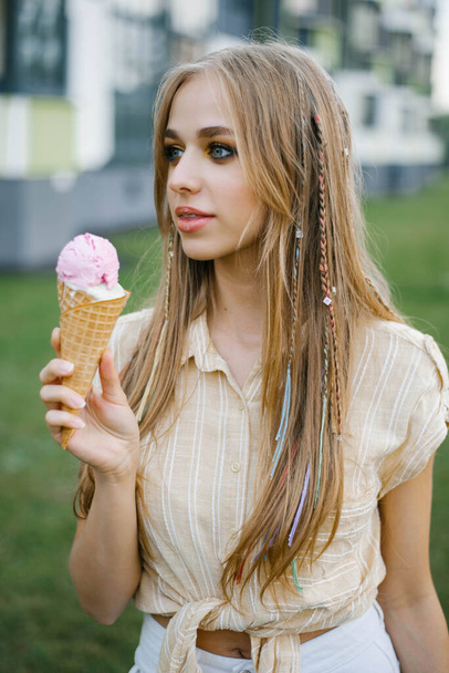 Cute girl eats ice cream from a waffle cone, soiling her lips - Photo, Image