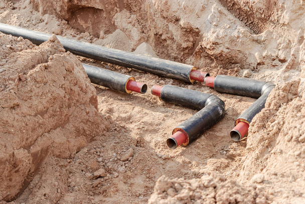 Laying heating pipes in a trench at construction site. Energy efficient insulated pipes. Cold and hot water, heating and heating system of apartments in the house - Photo, Image