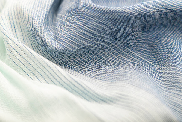 Фрагмент синьо-білої лляної тканини. Вид збоку, текстильний розмитий фон і текстура. Концепція води та хвилі
. - Фото, зображення
