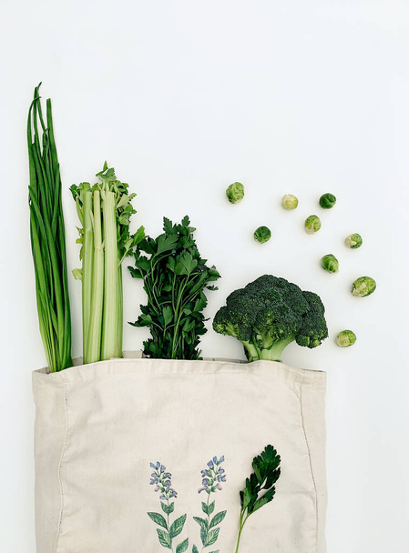 Vista dall'alto di verdure verdi in una borsa di cotone eco su sfondo bianco. - Foto, immagini