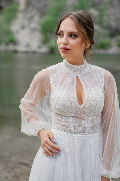 close up. The bride in a white dress on the bank of a mountain river. - Photo, image