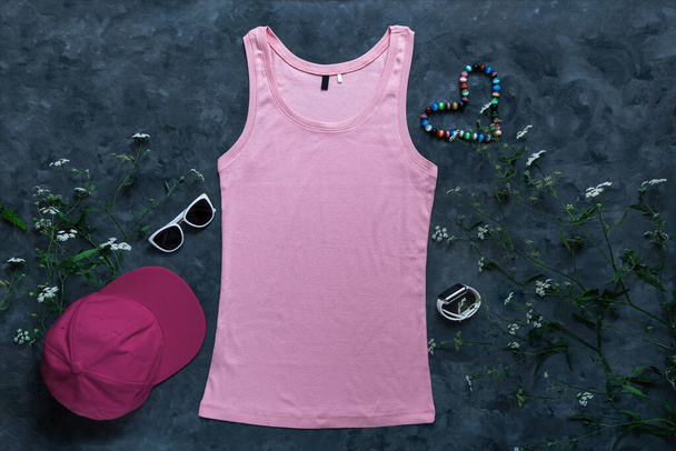 Розовый макет танка на темном фоне. Бланшированная простая футболка искушает креативным дизайном. Женские летние солнцезащитные очки одежда без рукавов майка. Казуальная бейсболка. - Фото, изображение