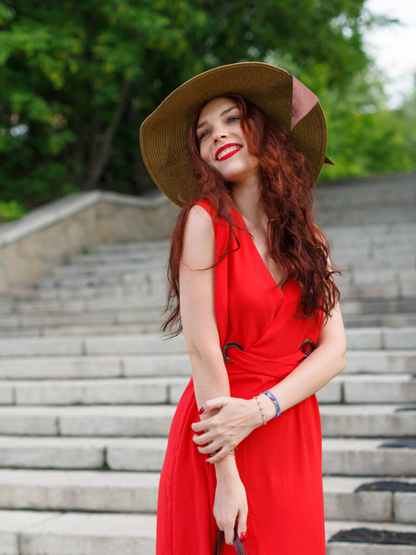 Geniş şapkalı mutlu genç bir kadın yazın parkta poz verir. - Fotoğraf, Görsel