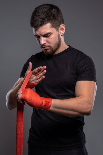 Hombre envolviendo hads con cinta de boxeo profesional roja - Foto, Imagen