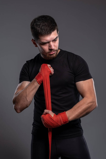 Young man wrapping hands with red boxing tape - Фото, изображение