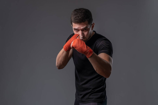 Focused young fighter with wrapped hands standing in orthodox stance - Photo, Image