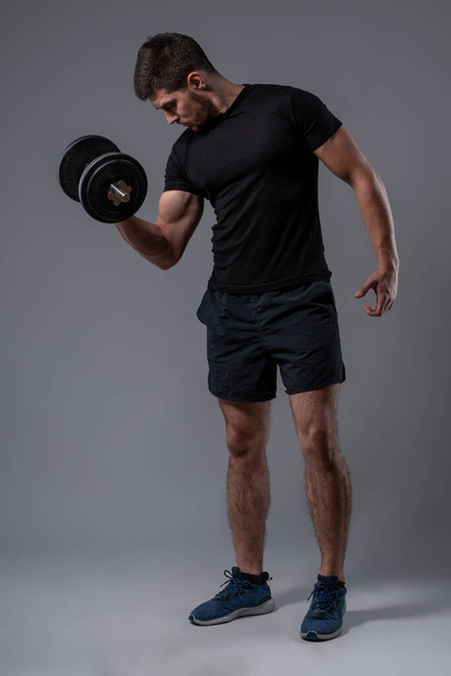 Atletický muž provádějící biceps cvičení s činkou - Fotografie, Obrázek
