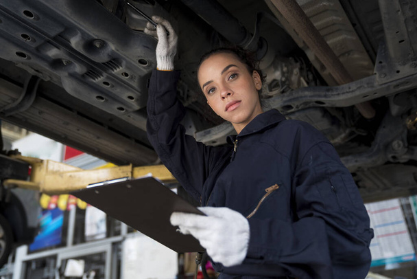 Szervizjavítási koncepció. Afrikai amerikai nő dolgozik autószerelő a garázsban ellenőrzése autó motor. - Fotó, kép