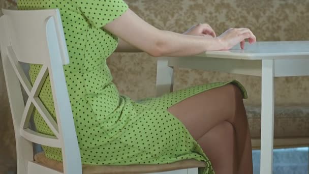 Dziewczyna siedzi przy stole i nerwowo stuka palcami, śledząc kamerę - Materiał filmowy, wideo