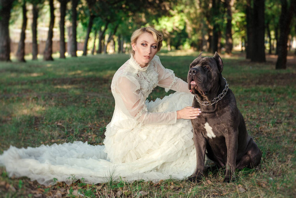 Menina em um vestido velho com babados e um grande cão escuro - Foto, Imagem