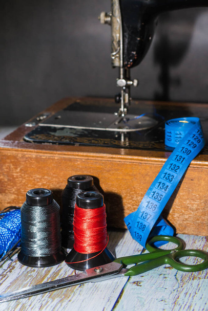 Šicí příslušenství šicí stroj, barevné nitě, stejně jako nůžky a měřicí páska - Fotografie, Obrázek