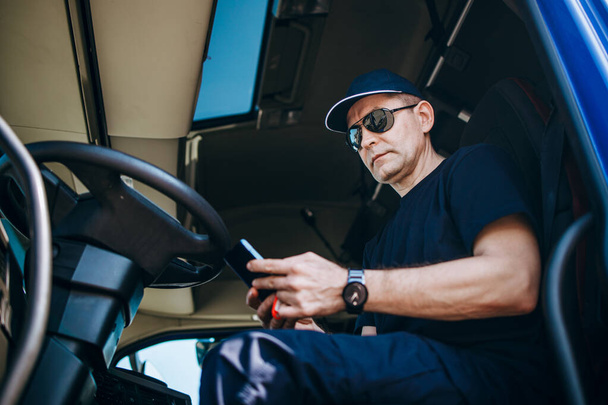 Experienced truck driver sitting in his truck and waiting for a new driving route.  - Zdjęcie, obraz