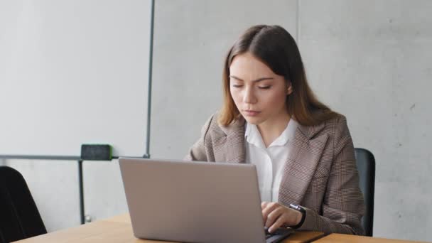 Молода тисячолітня кавказька бізнес-менеджерка студентка-працівниця, яка сидить в офісі, друкуючи звіт про роботу ноутбука з комп'ютером засмучена проблемами з'єднання з низькою батареєю, втрачаючи поразку
 - Кадри, відео