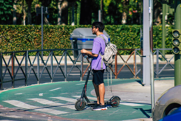 Seville Spain July 02, 2021 People rolling with an electric scooter in the streets of Seville, operating with a small utility internal combustion engines and a deck in the center - Foto, Bild