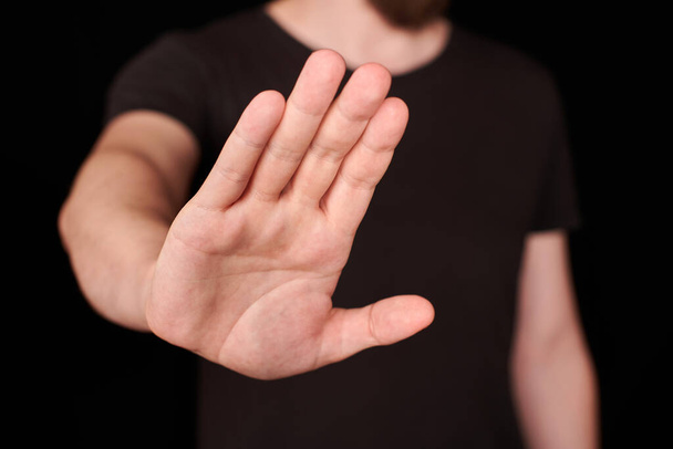 Stop signe de la main. Un homme en t-shirt noir qui arrête de chanter. Dites NON, rejetez le concept. - Photo, image