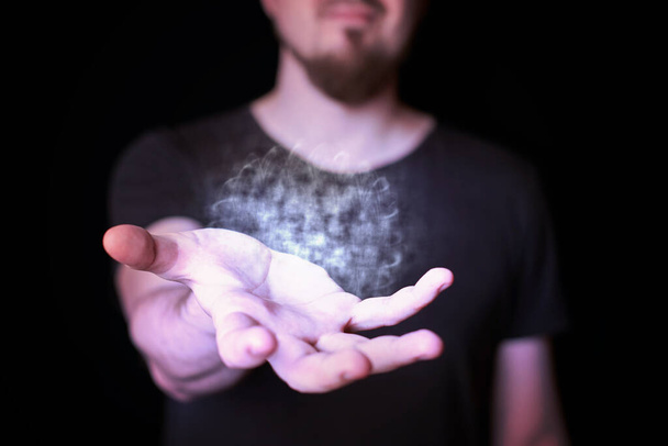Energy ball in wizard hand. Bearded man casting bright magic ball spell. Black background - Foto, Imagen