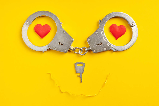 Bilincs mosoly alakú sárga háttér. Szabadság koncepció. A szabadságvesztés, a szabadságelvonás és az elkövetők letartóztatása. - Fotó, kép