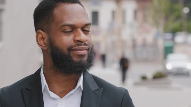 Headshot smiling bearded millennial African businessman looks at camera. Ambitious corporate staff member in formal suit pose outdoors. Career growth, hired employee, company founder portrait concept - Footage, Video