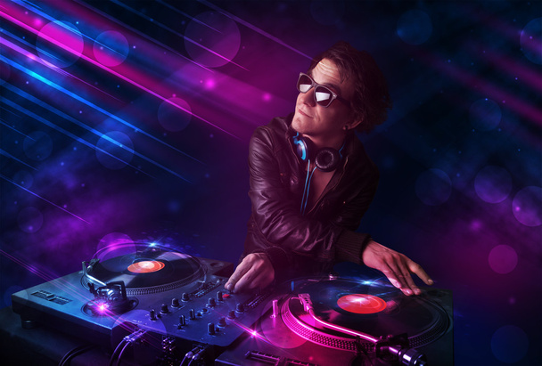 Молодой DJ играет на проигрывателях с цветовыми световыми эффектами
 - Фото, изображение