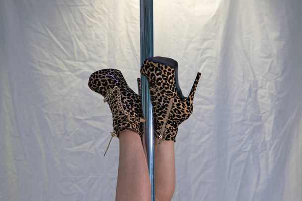 Detail van paaldanserspoten met luipaardhakken. De voeten zijn verstrikt in de paal terwijl de paal ondersteboven wordt gehouden. Dansconcept - Foto, afbeelding