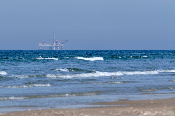 Ameland, Nederland 20 april 2021-NAM, Olieplatform, offshore platform met strand, zand en surfen. Aardgaswinning in het Waddengebied, Waddeneiland, natuurbeschermingsgebied: Het Oerd. - Foto, afbeelding