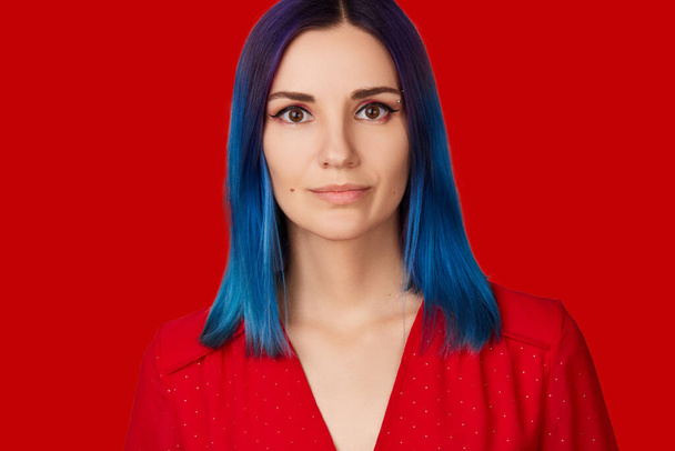 Onnellinen nuori nainen punaisessa mekossa siniset hiukset punaisella taustalla - Valokuva, kuva