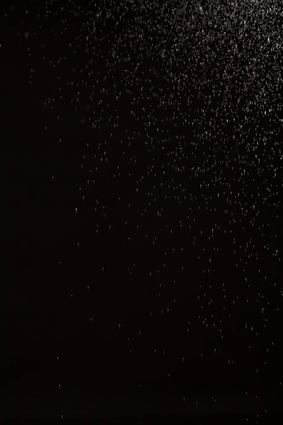 Αφηρημένο φόντο με μικρές σταγόνες. Ένα εναιώρημα μικρών λευκών σωματιδίων απλώνεται από την πάνω δεξιά γωνία προς τα κάτω σε ένα γκρίζο backgroun - Φωτογραφία, εικόνα