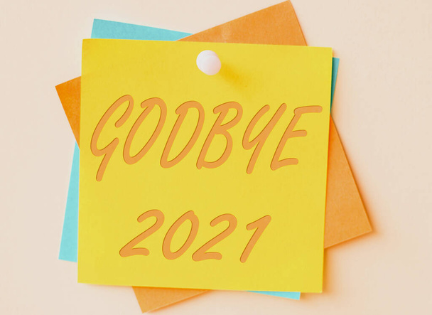 Fogalmi felirat Godbye 2021. Üzleti koncepció kifejezni jó kívánságait, amikor elválnak, vagy a végén a tavalyi színes papír jegyzetek egymásra, és tűzve a falon. - Fotó, kép