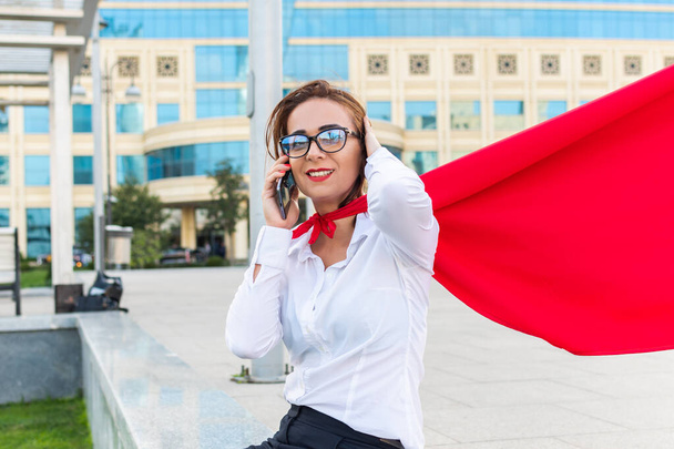 succesvolle zakenvrouw praten met telefoon in superheld cape - Foto, afbeelding
