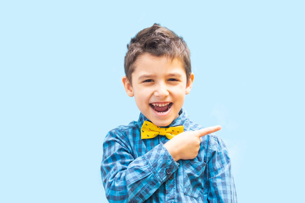 menino alegre mostra um gesto de dedo. Retrato de um menino em um fundo azul - Foto, Imagem