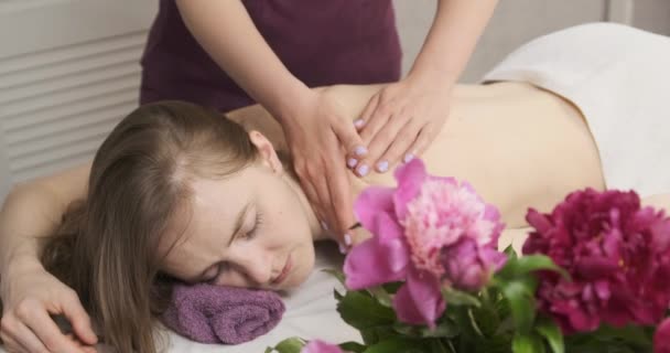 Les mains d'une masseuse font doucement un massage à une belle jeune femme. Agréable salon de spa, prenant soin du corps - Séquence, vidéo
