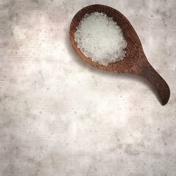 square stylish old textured paper background with a wooden spoon full of seasalt - Фото, изображение