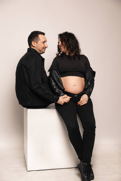 Beautiful happy couple is expecting a baby. A married couple expecting a child in a photo studio. - Valokuva, kuva