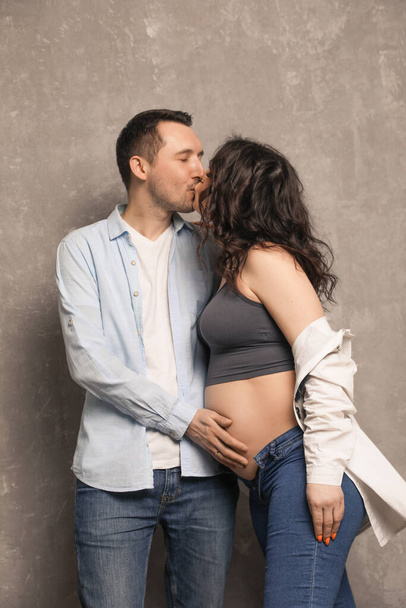 Beautiful happy couple is expecting a baby. A married couple expecting a child in a photo studio. - Fotó, kép