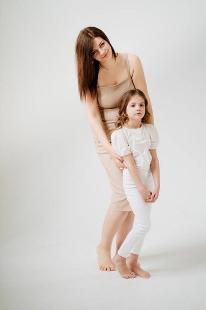 Mom and daughter pose in a white photo studio. - Foto, Imagem