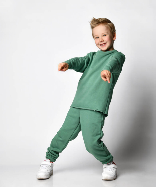 emotional portrait of Caucasian teenage boy in tracksuit. Surprised teenager looking at camera. Beautiful happy baby isolated on white background. - Photo, Image