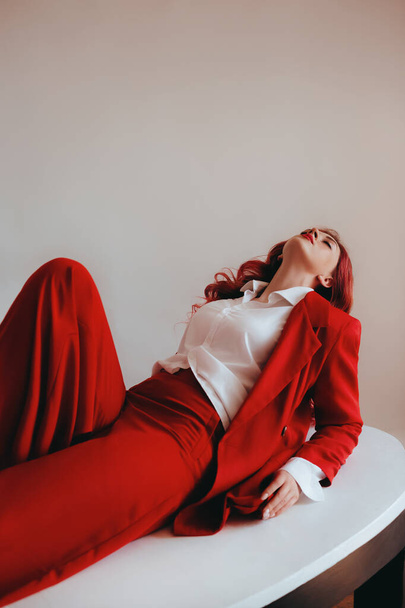 Prachtige vrouw in een elegant rood pak met rood haar. Natuurlijke vrouwelijke schoonheid. - Foto, afbeelding