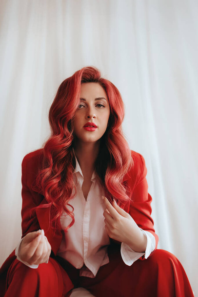 Preciosa mujer en un elegante traje rojo con pelo rojo. Belleza femenina natural. - Foto, Imagen