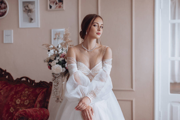 Beautiful bride with light make-up in white dress  in an exquisite interior  - Photo, image