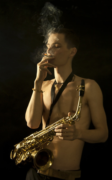 Smoking young jazz man with saxaphone - Foto, Imagen