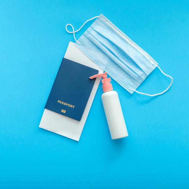 Safe travel flights during covid and coronavirus lockdown. Protective medical mask sanitizer and passport airplane ticket flat lay on color blue background with copy space. Squere - Foto, Bild