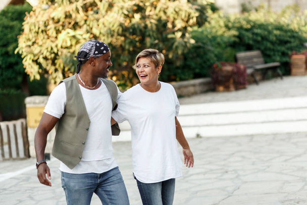 Смешанная гонка улыбающаяся пара наслаждается отпуском, турист весело гуляет и исследует городскую улицу в течение дня. отдых в разнообразии и любви концепции - Фото, изображение