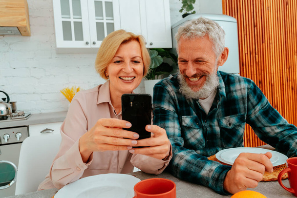 couple has breakfast at home and read something from smartphone - Zdjęcie, obraz